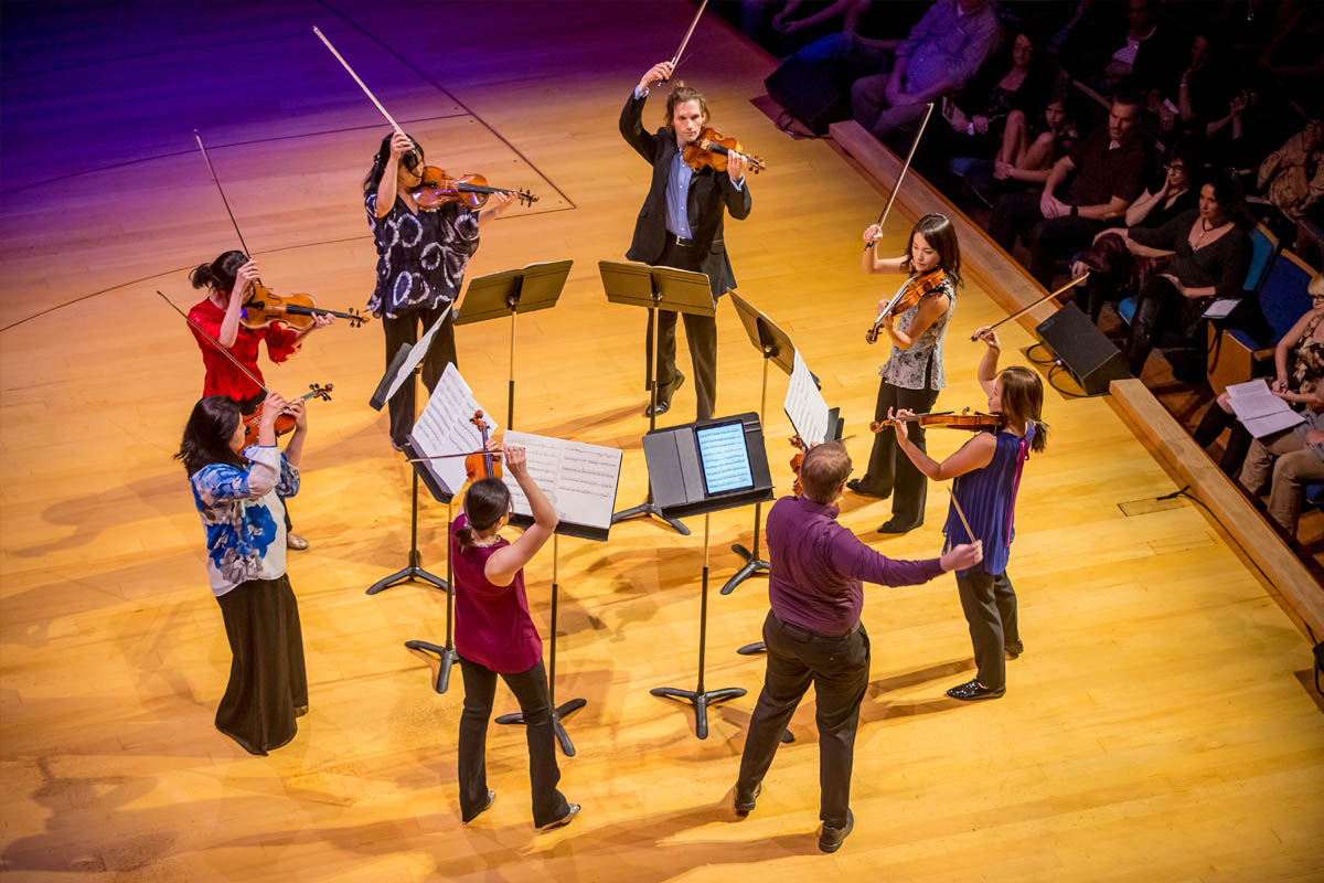 eight violinists performing on stage