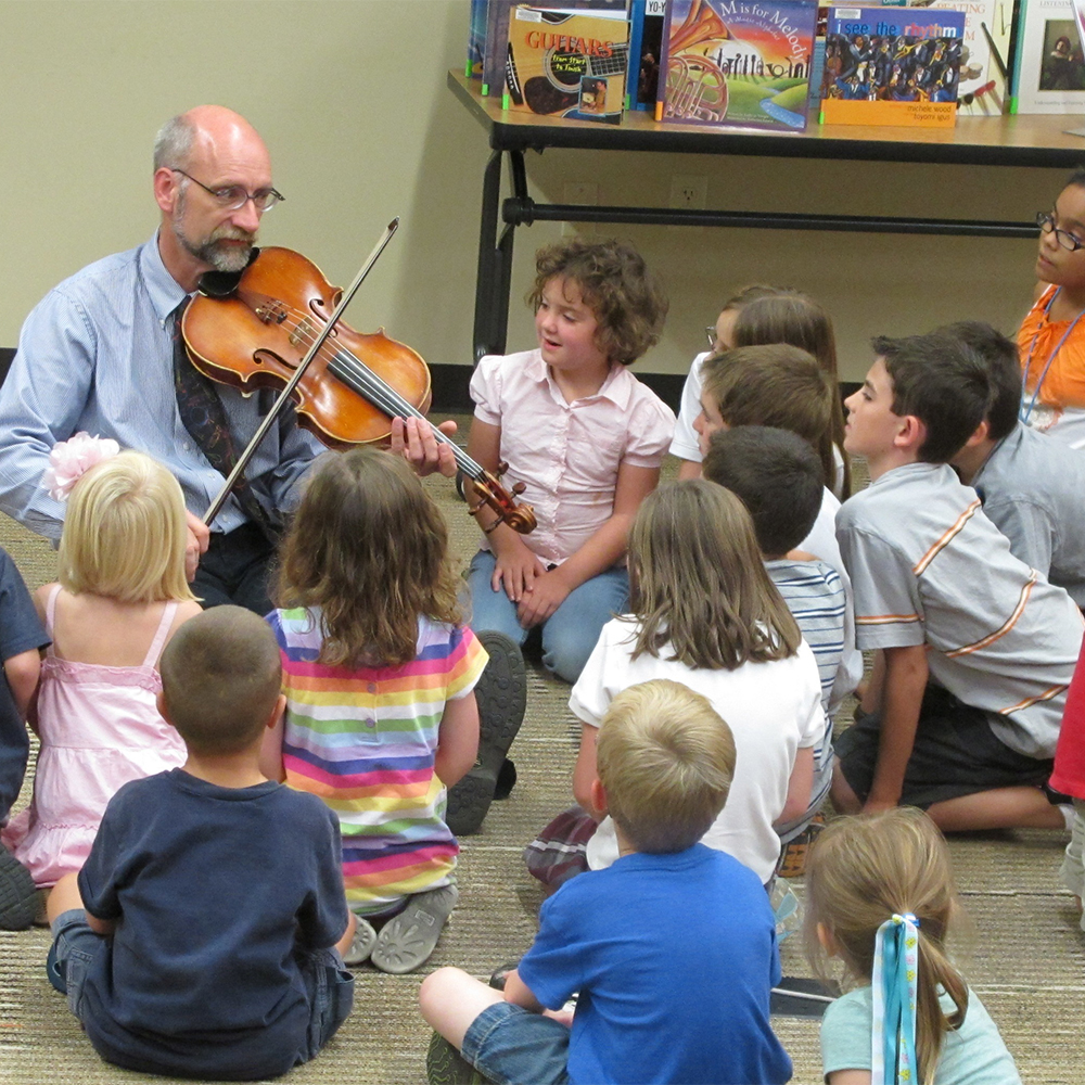 man playing violin with children