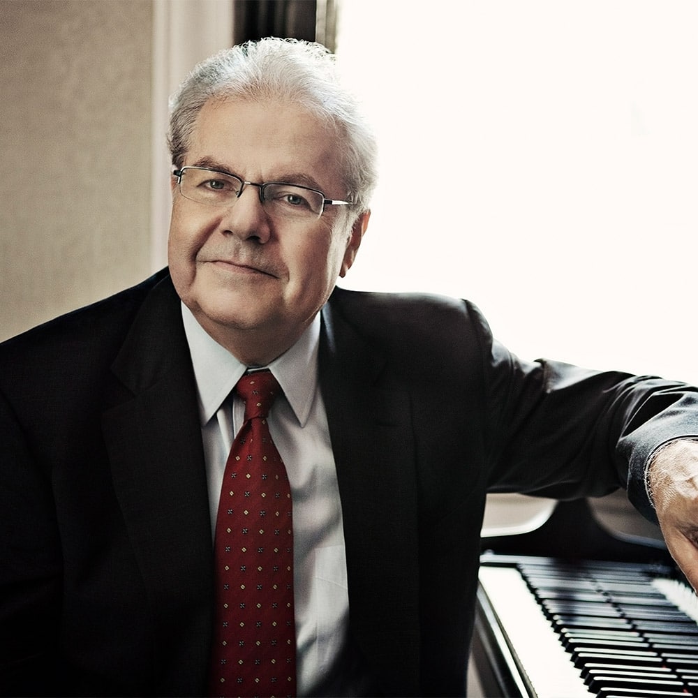 Portrait of Emanual Ax sitting at his piano