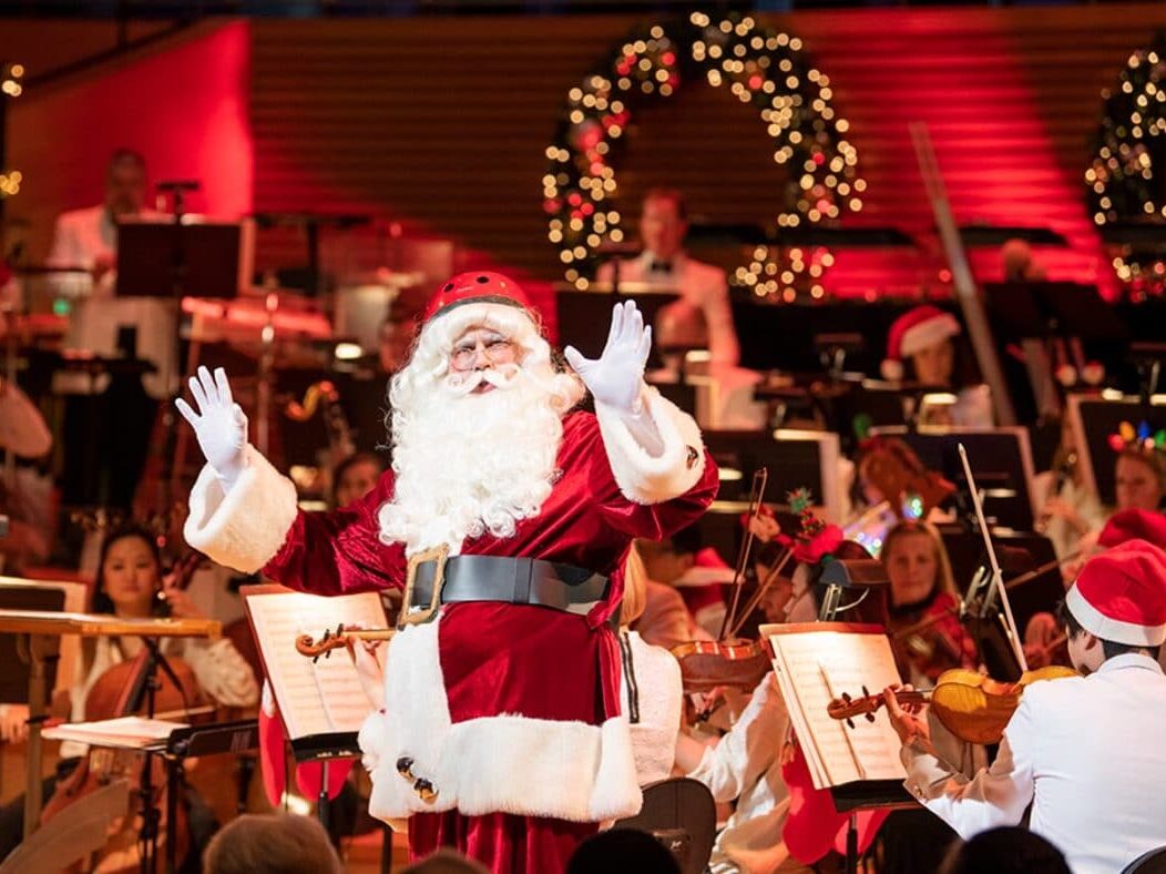 Photo of Jason Seber, Santa Claus and the Kansas CIty Symphony on stage in Helzberg Hall at Christmas Festival